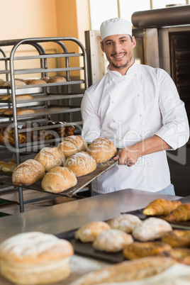 Happy baker taking out fresh loaves