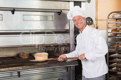 Happy baker taking out fresh loaf