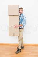 Smiling man carrying pile of cardboard moving boxes