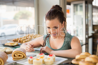 Pretty brunette looking at cakes