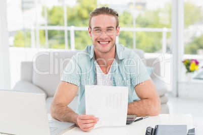 Happy businessman sitting at his desk holding document