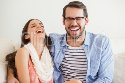 Young couple smiling at camera on couch