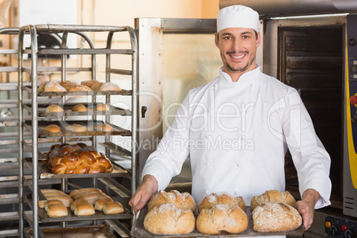 Happy baker showing tray of fresh bread