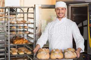 Happy baker showing tray of fresh bread