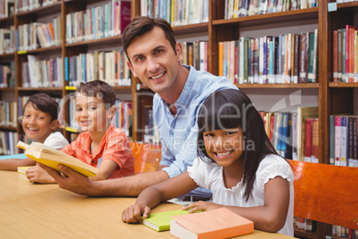 Cute pupils and teacher reading in library