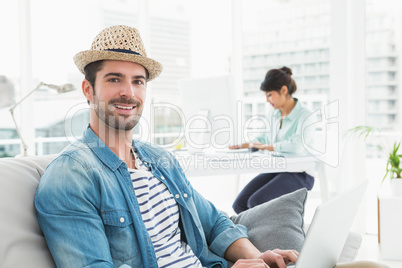 Smiling businessman typing on laptop on couch