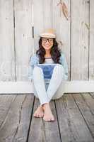 Pretty hipster sitting on ground with tablet