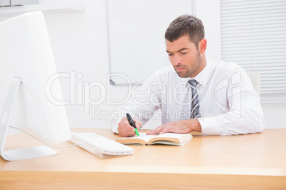 Businessman sitting at desk reading a book