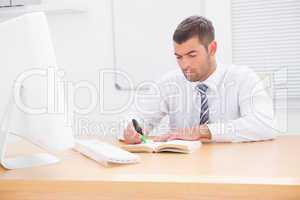 Businessman sitting at desk reading a book