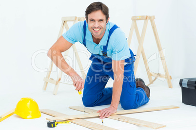 Happy repairman fixing screw on plank