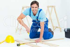 Happy repairman fixing screw on plank