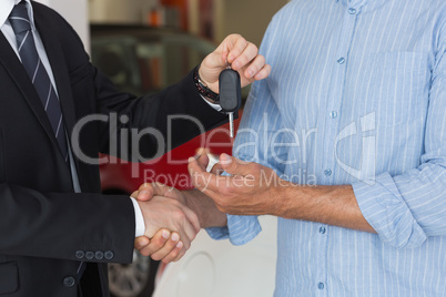 Businessman giving car key while shaking a customer hand