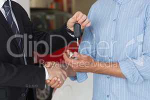 Businessman giving car key while shaking a customer hand