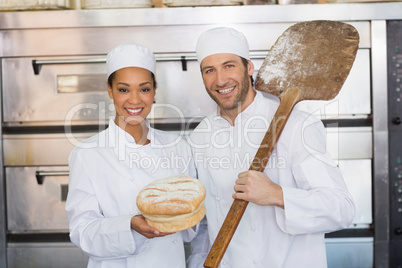 Team of bakers smiling at camera with loaf