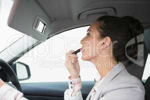 Woman using mirror to put on lipstick while driving