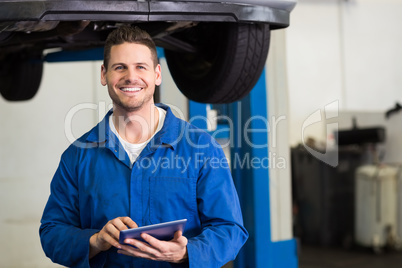 Smiling mechanic looking at camera using tablet