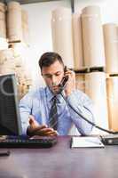 Warehouse manager using cellphone and laptop