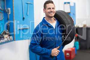 Mechanic smiling at the camera holding tire