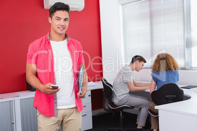 Student holding notebook and phone near classmates