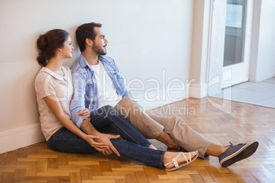 Cute couple sitting on floor against wall