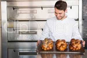 Happy baker showing tray of fresh bread