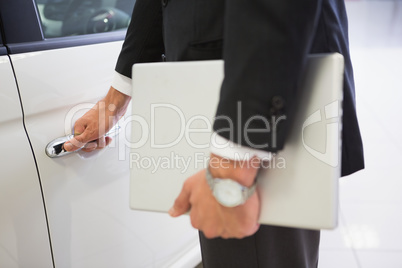 Man holding a car door handles with a laptop