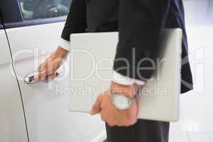 Man holding a car door handles with a laptop