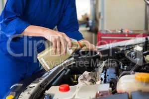 Mechanic pouring oil into car