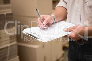 Warehouse worker checking his list on clipboard