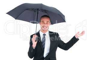 Businessman sheltering under black umbrella