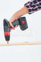 Male carpenter drilling hole in wood