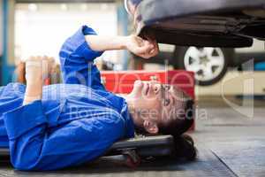 Mechanic lying and looking under car