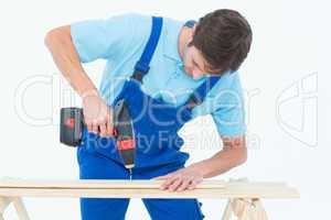 Carpenter using drill machine on wood