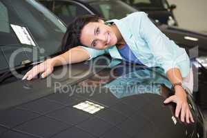 Smiling woman hugging a black car