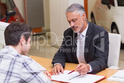 Salesman showing client where to sign the deal