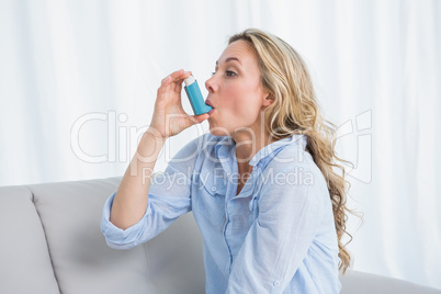 Blonde using her asthma inhaler on couch