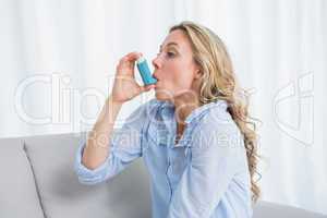Blonde using her asthma inhaler on couch