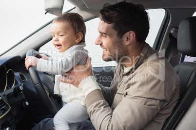 Father playing with baby in drivers seat