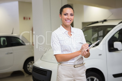 Smiling businesswoman writing on clipboard