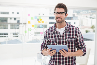 Happy businessman with glasses holding tablet