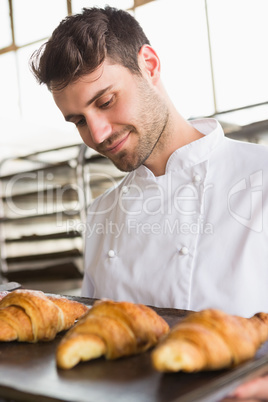 Baker showing tray of fresh croissant