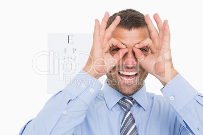 Businessman surrounds his eyes with fingers