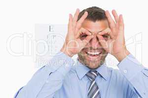 Businessman surrounds his eyes with fingers