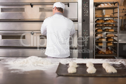 Baker opening oven to put the dough in
