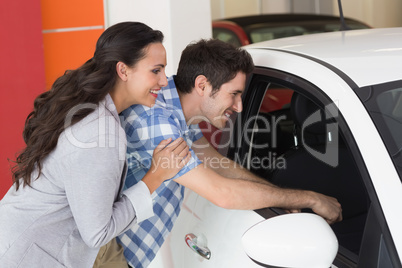 Smiling couple looking inside a car