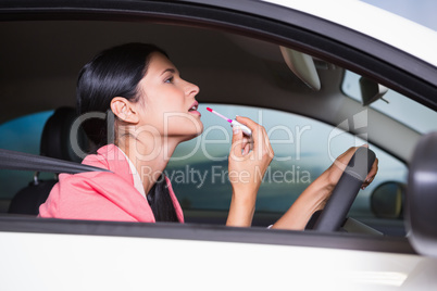 Woman using mirror to put on lipstick while driving