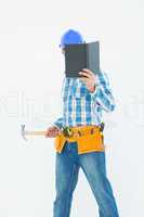 Carpenter reading book while holding hammer