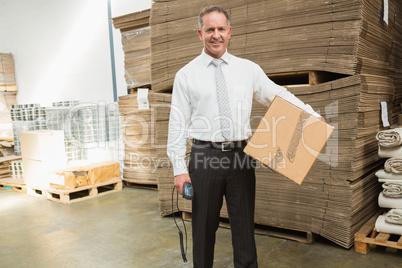 Warehouse manager holding cardboard box and scanner