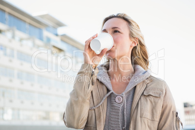 Beautiful blonde drinking of disposable cup