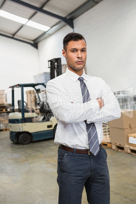 Serious manager with arms crossed in warehouse